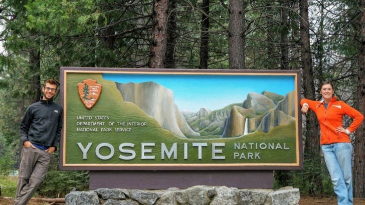 tom morton and cait morton standing at the yosemite national park sign