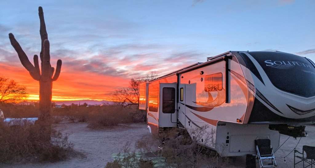 RV parked in sunset in desert.