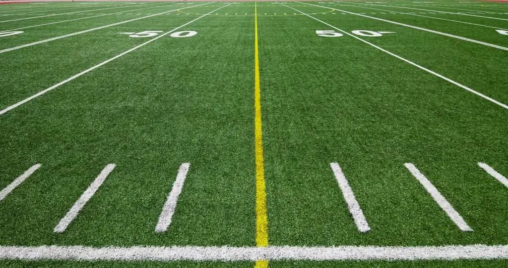 Close up of the 50 yard line of a football field.
