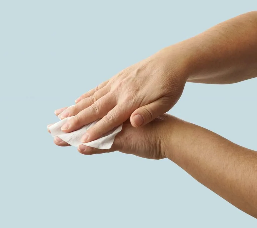 Woman washing hands with a body wipe.