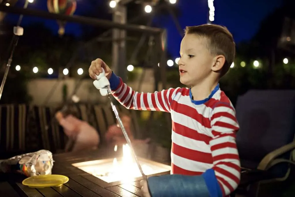 Little boy putting marshmallows on his metal roasting stick.