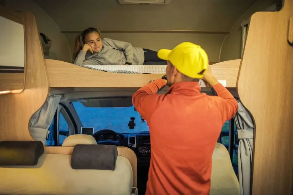Man with his daughter inside bunk house travel trailer.