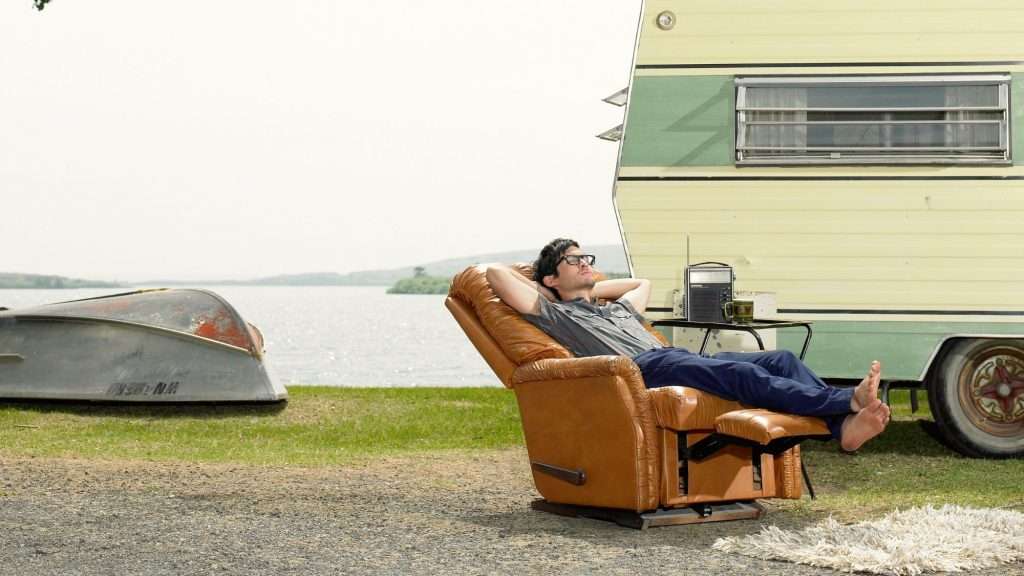 Man napping in a recliner at a campsite