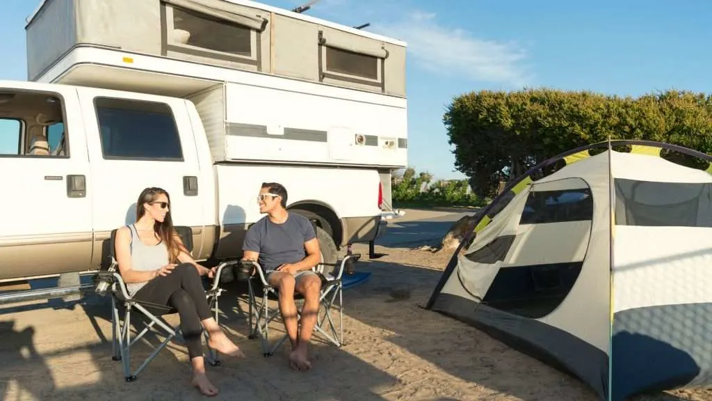Couple sitting in front of a pop-up truck camper