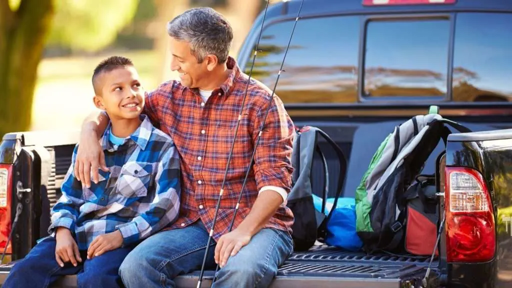Father and son sitting on truck tailgate