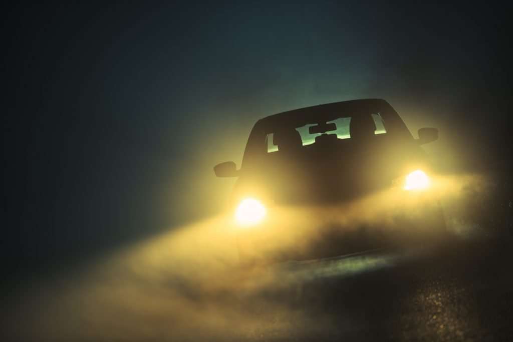 Car Driving in Dense Fog with yellow lights.