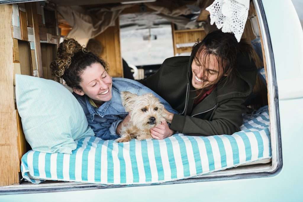 Happy couple and dog laying in their camper van