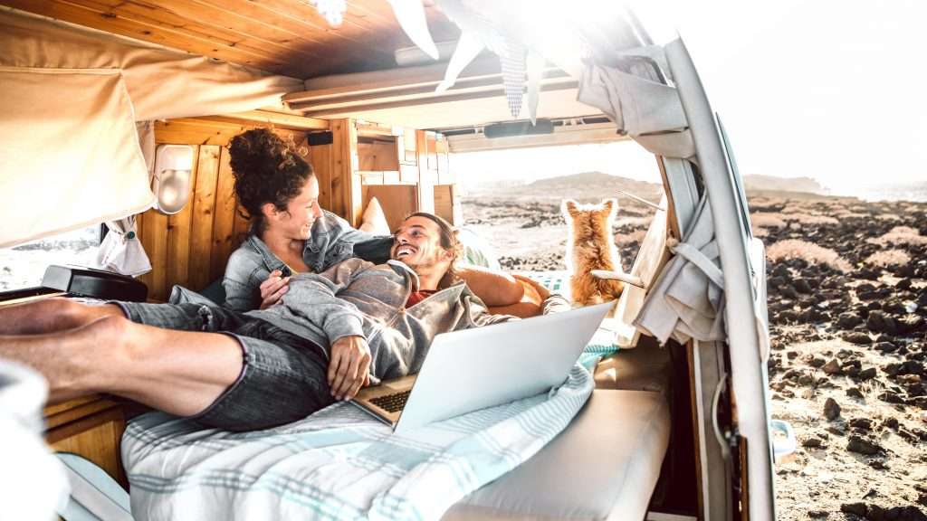 Happy couple and dog laying in their minivan camper.