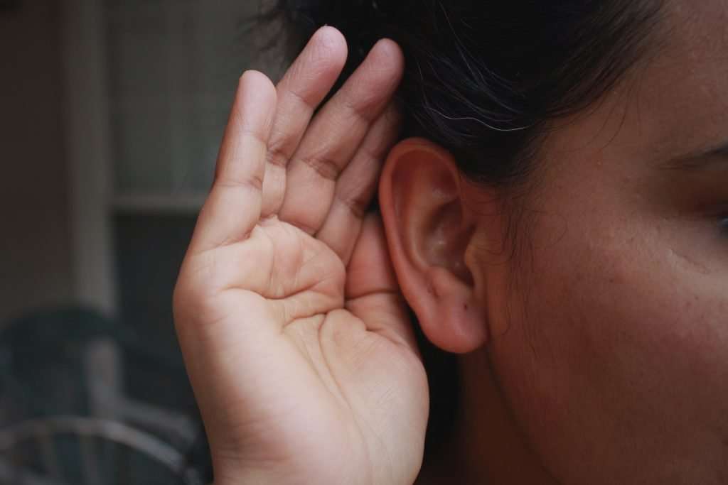 Woman cupping ear listening for sounds of her heat pump.