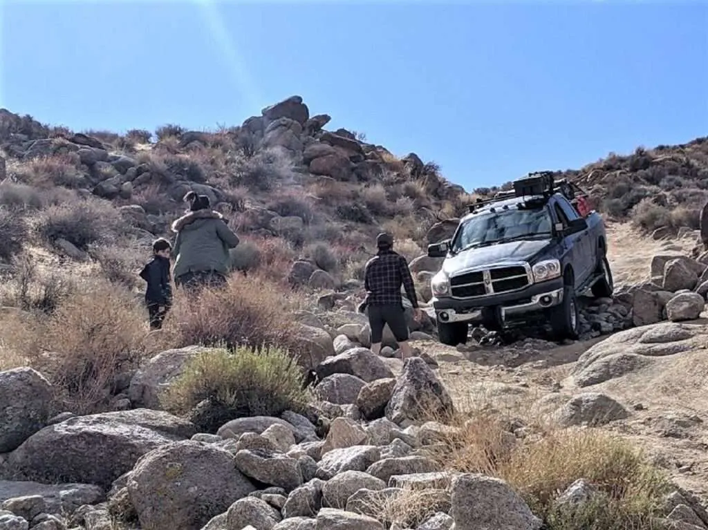 Group of friends driving truck over rocks while overlanding.