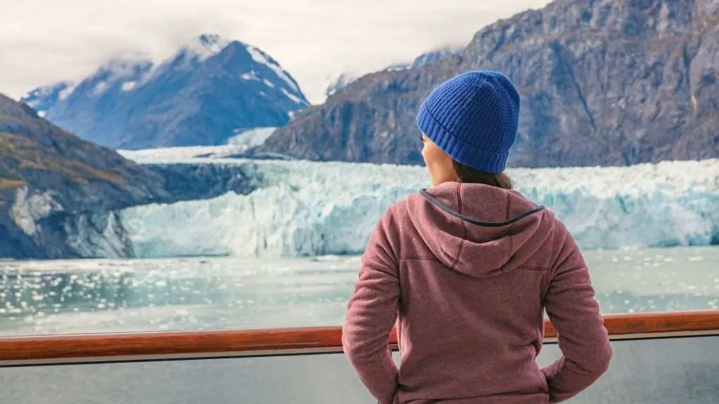 Woman viewing the Alaska coastline from a cruise ship deck