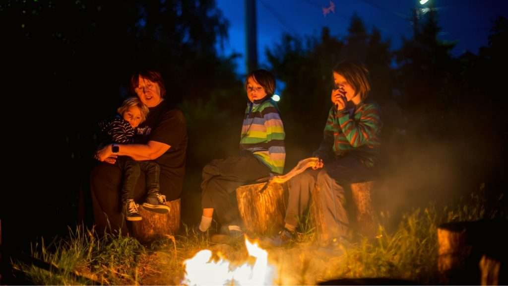 Kids and grandmother sitting around campfire