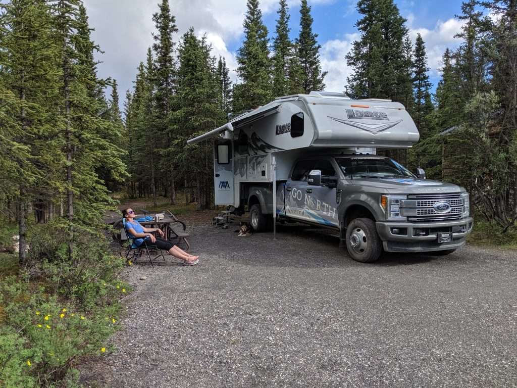 Caitlin Morton relaxing next to Go North truck camper with awning out.