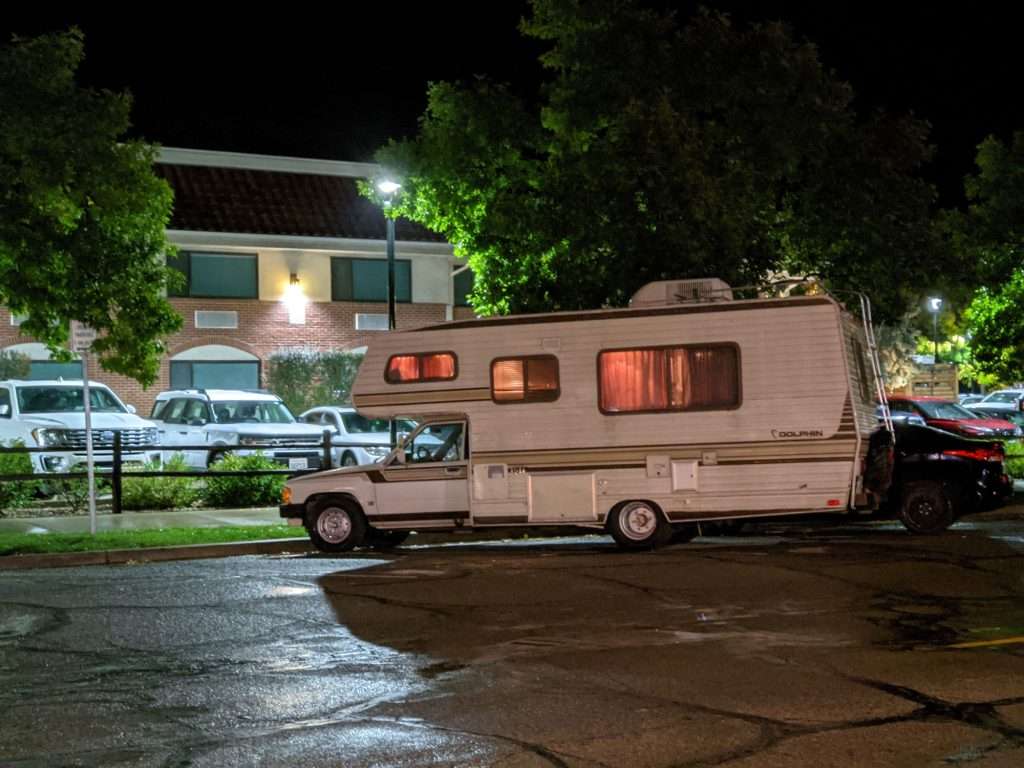 class c motorhome parked in street with  lights on inside