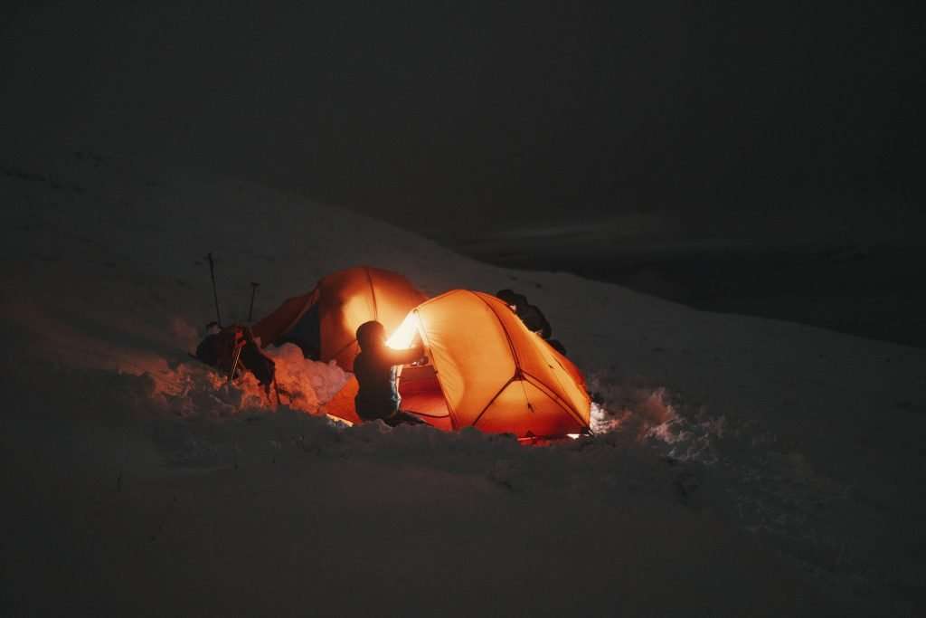 Friends setting up campsite in the snow.