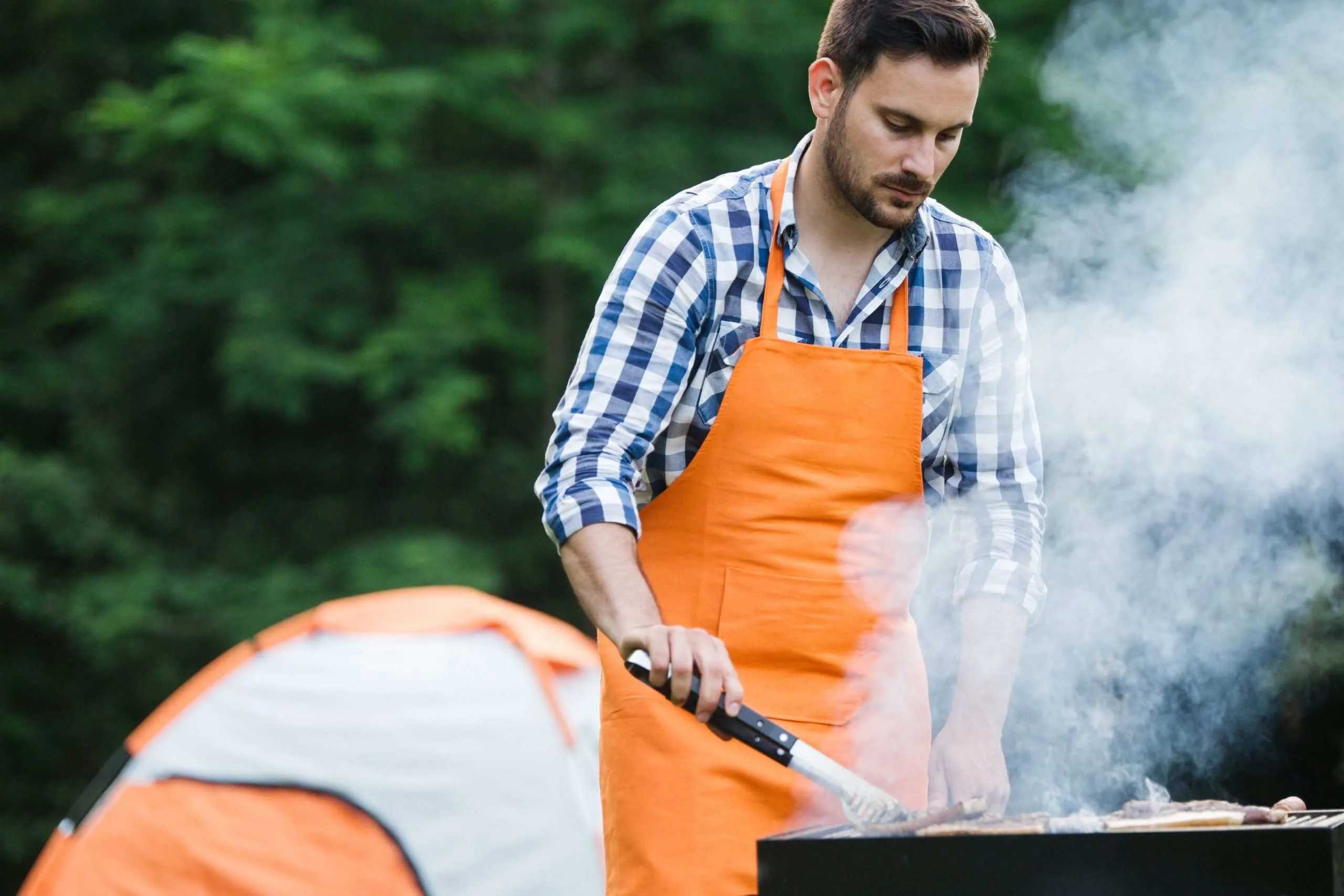 Man grilling in front of tent