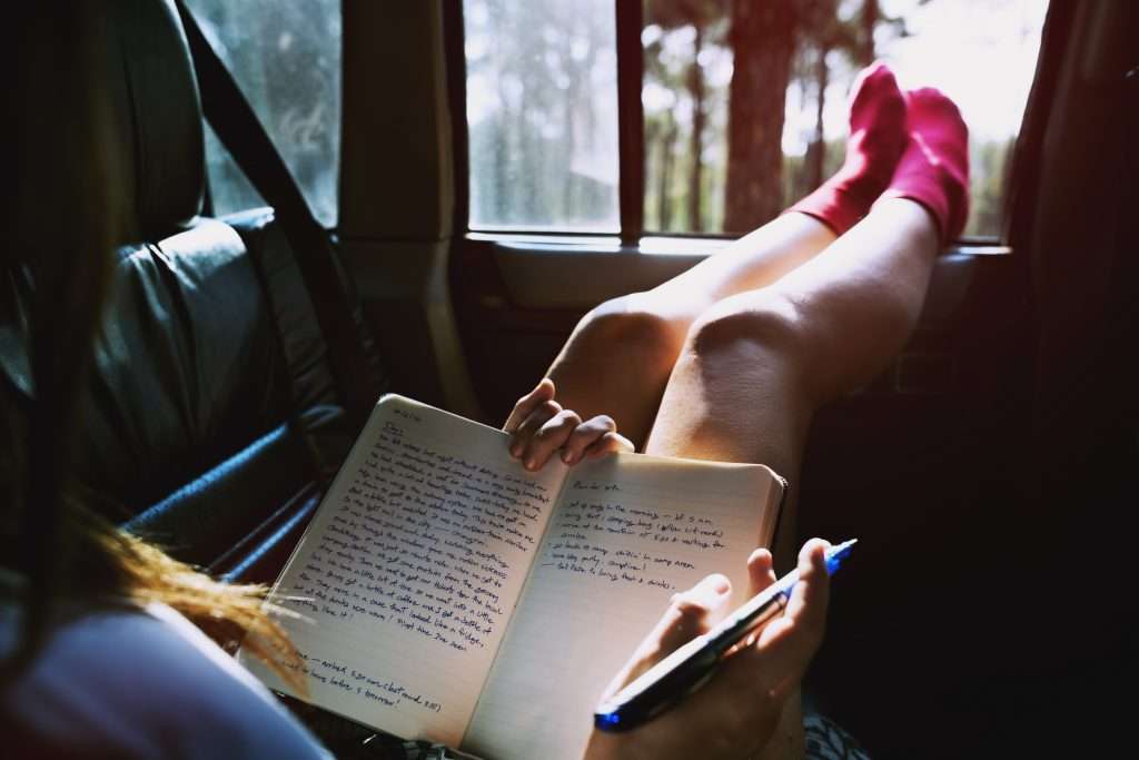 Girl journaling in car while car camping