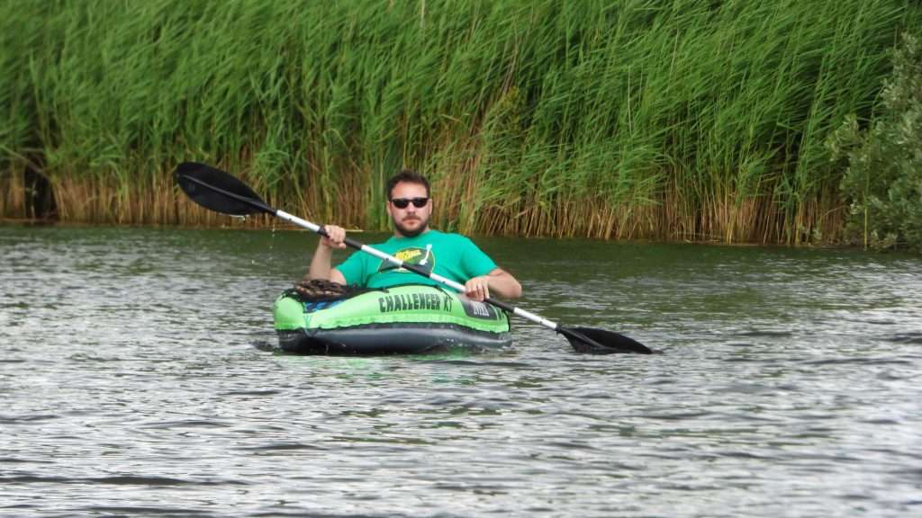 Man kayaking in the river in inflatable kayak.