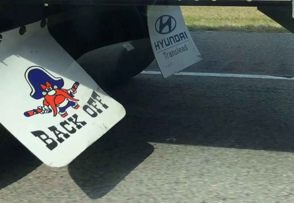 Close up of mud flaps on truck that say back off.