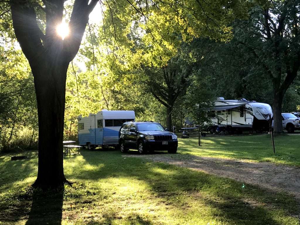 SUV and RV parked at campsite.