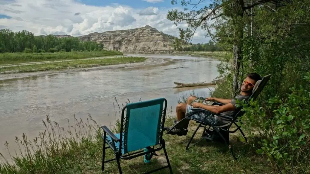 Tom relaxing in camping chair by river.