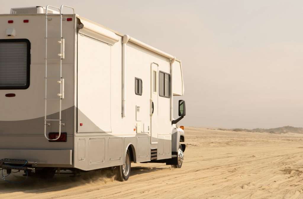 RV driving on beach for camping.
