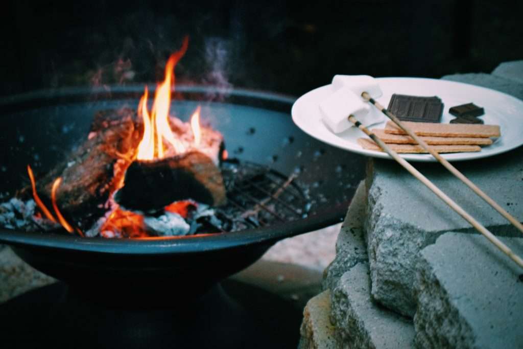 smore ingredients on plate next to campfire