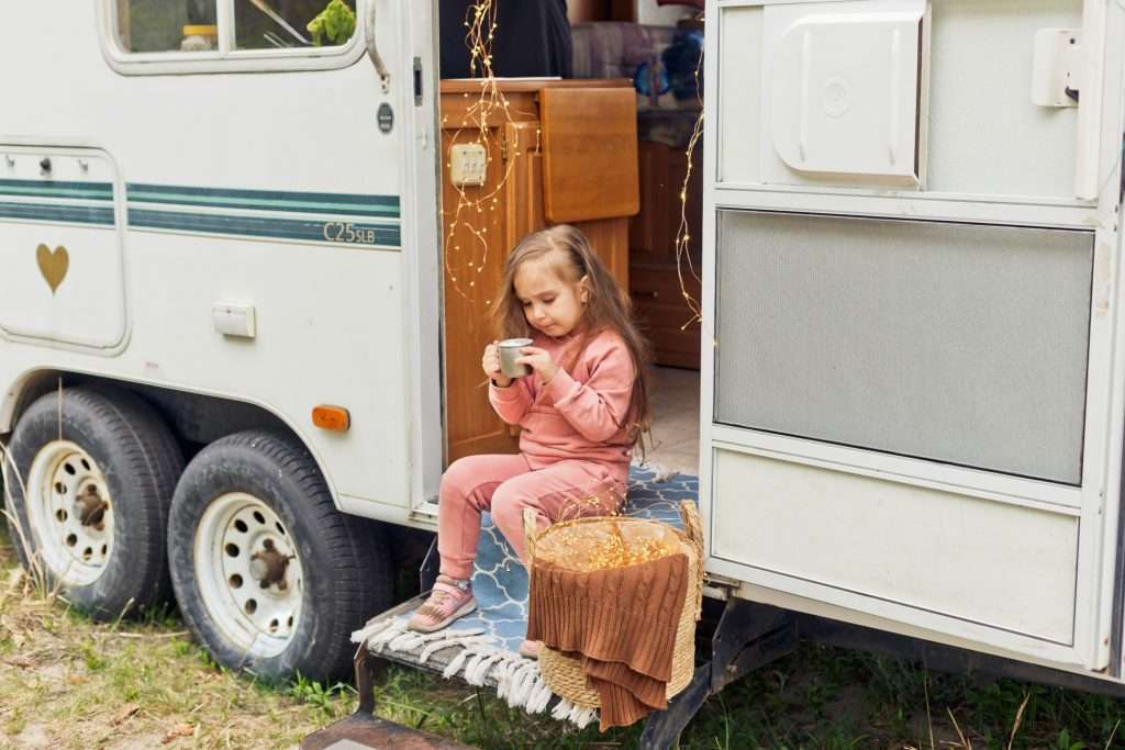 Girl drinking tea on the steps of a trailer.