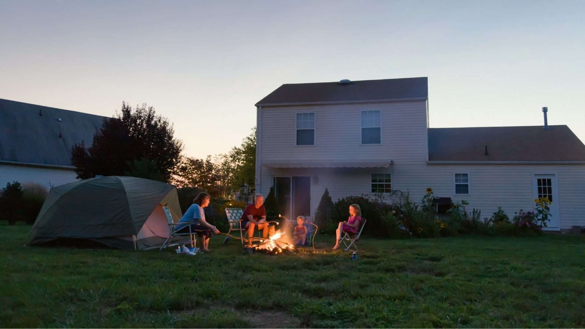 family sitting around a backyard campfire