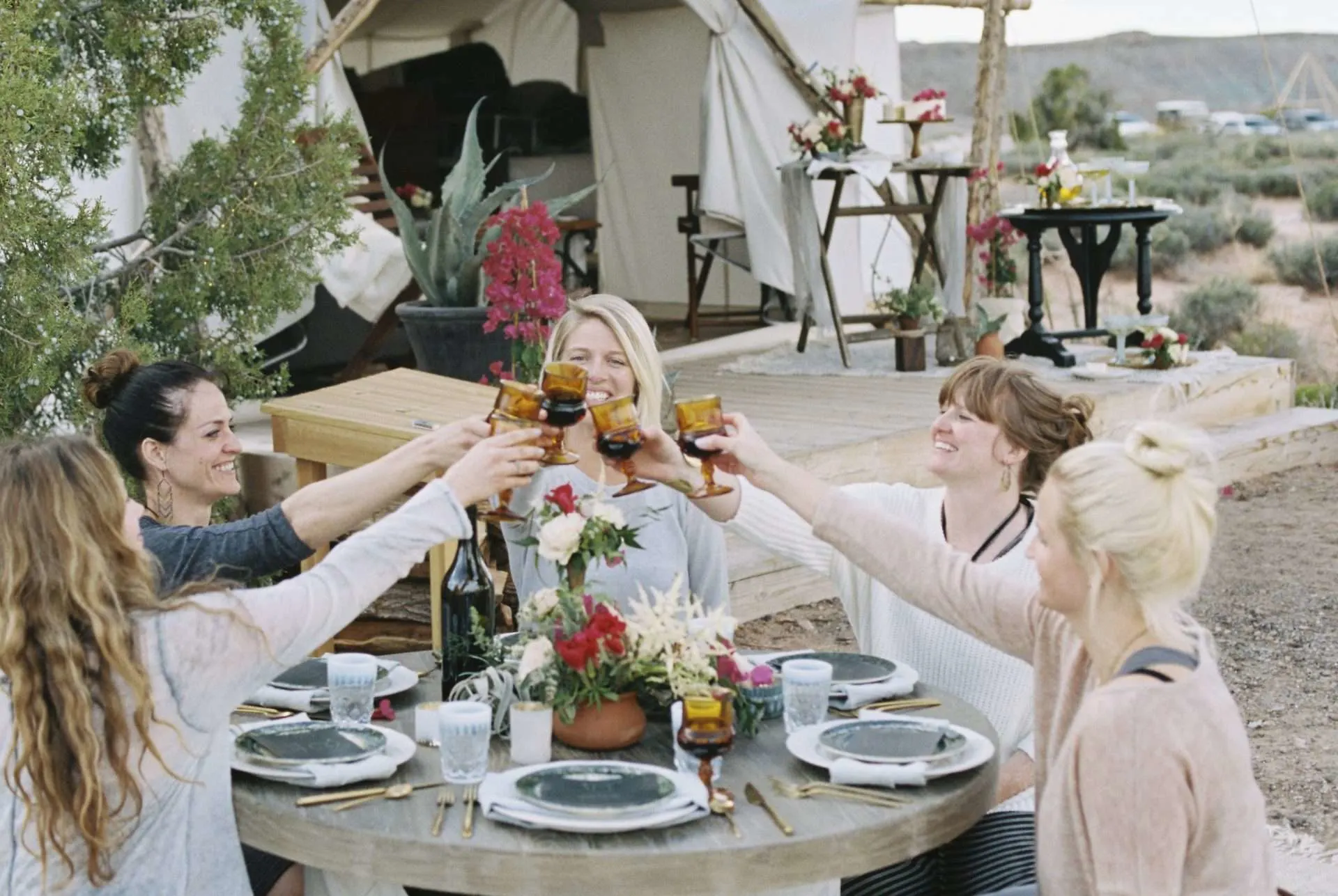 Woman toasting each other at a glamping site.