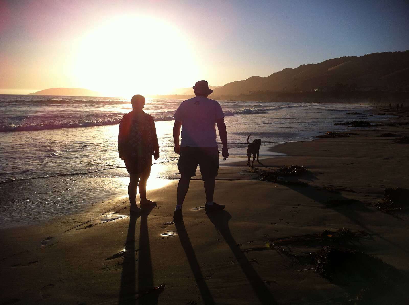 Couple and dog walking on Pismo Beach.