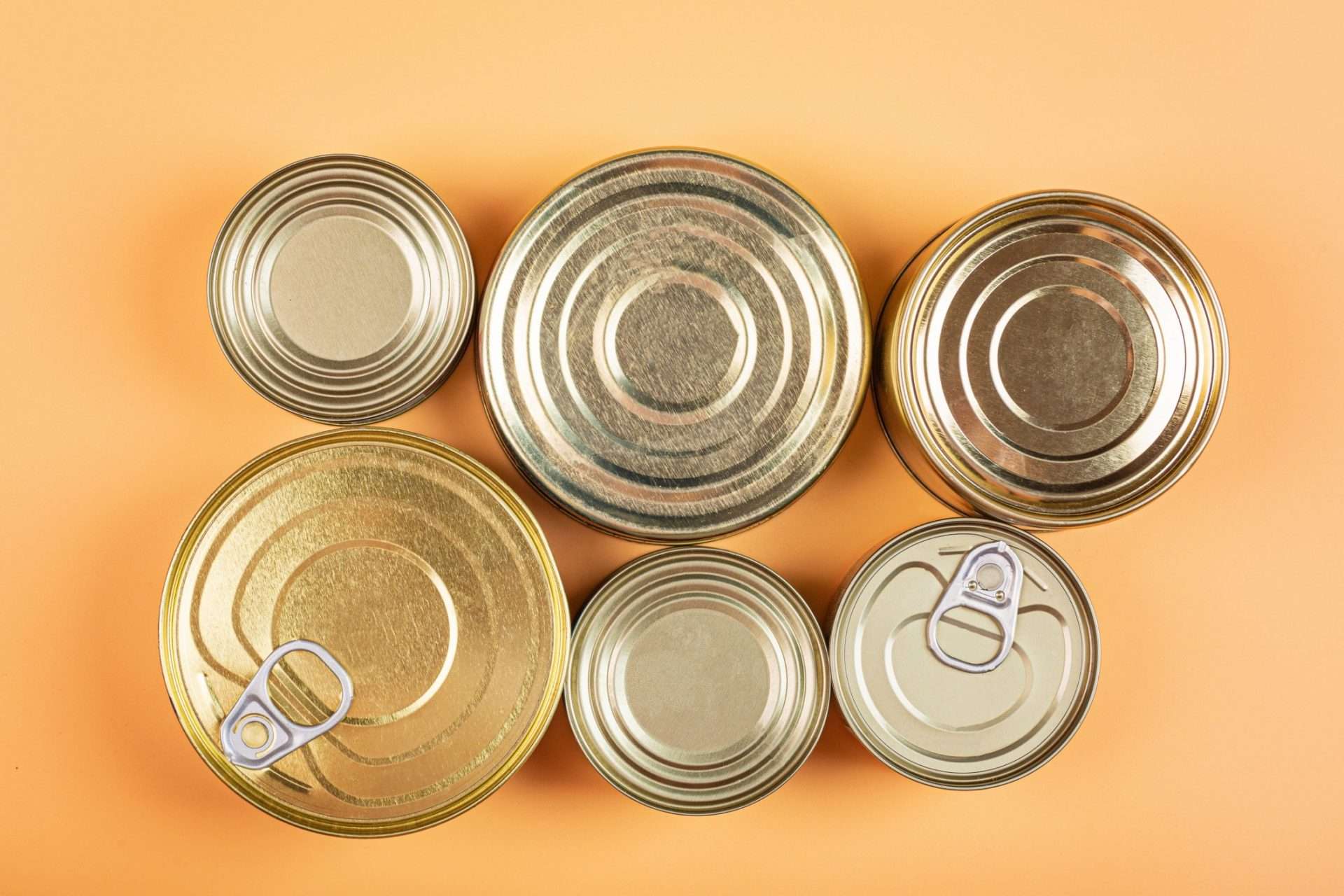 Overhead view of tops of cans on orange background