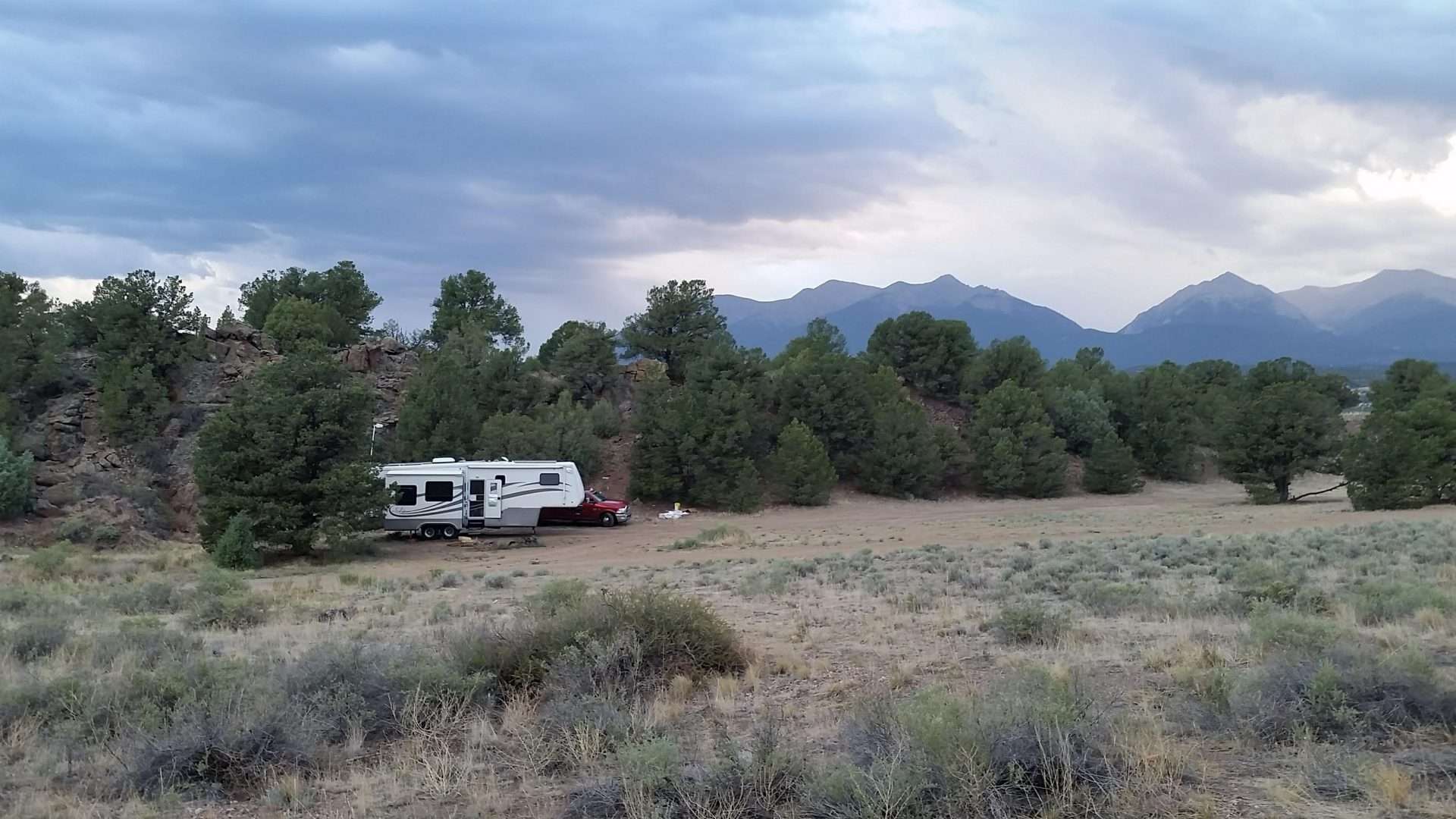 Mortons on the Move truck and fifth wheel parked in isolated camping spot by mountains.