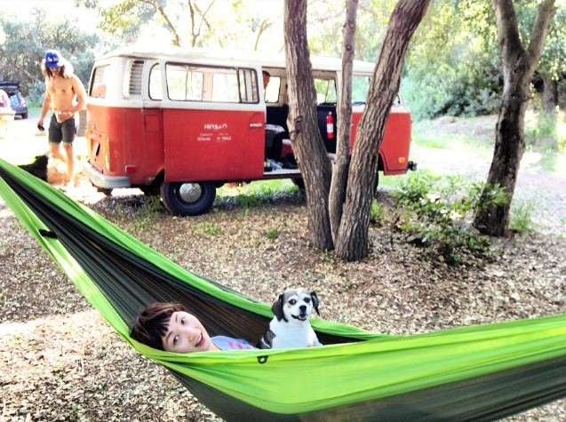 Woman and dog in hammock at camping site