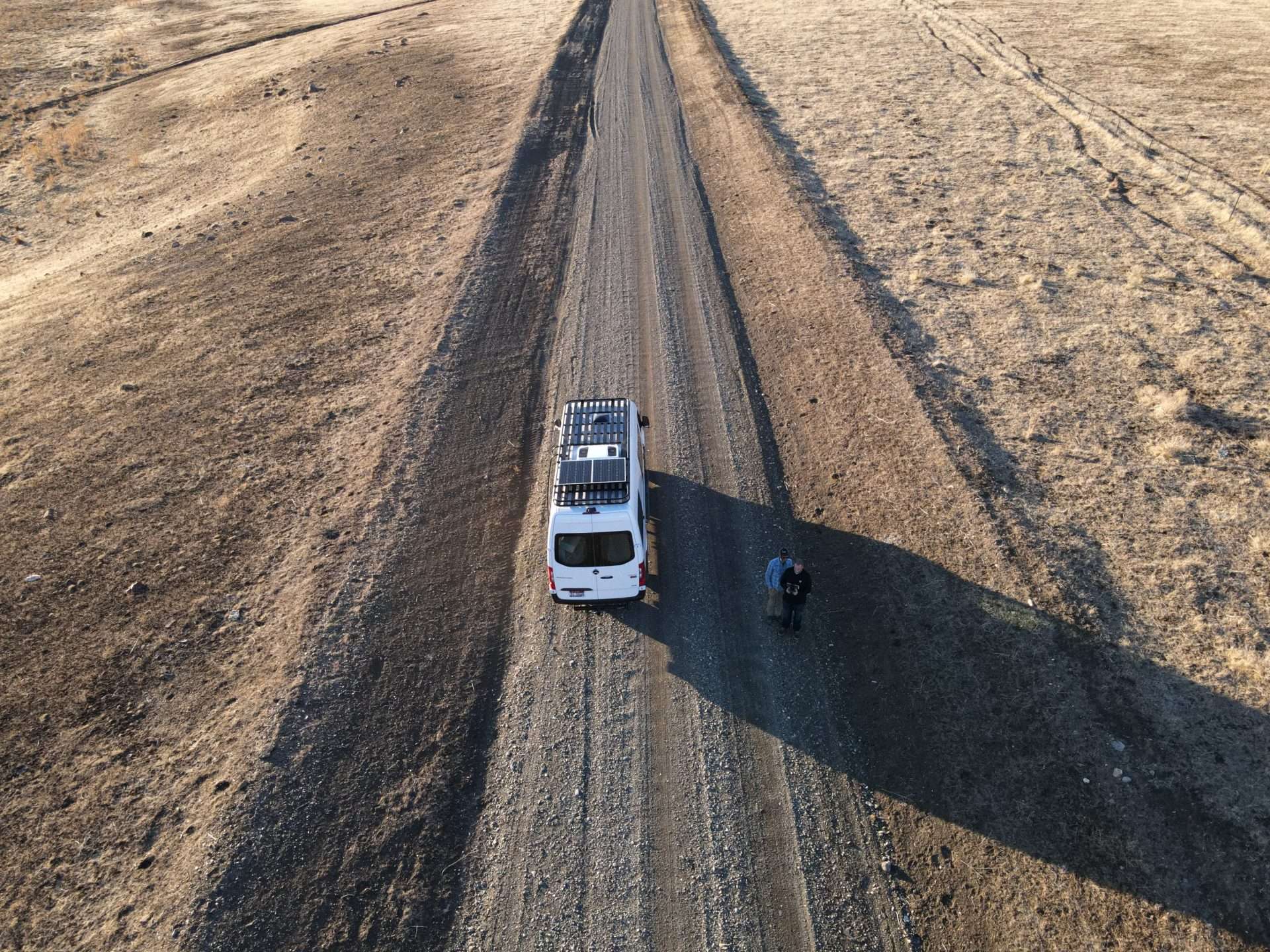 Aerial image of camper van driving down dirt road with solar panels installed.