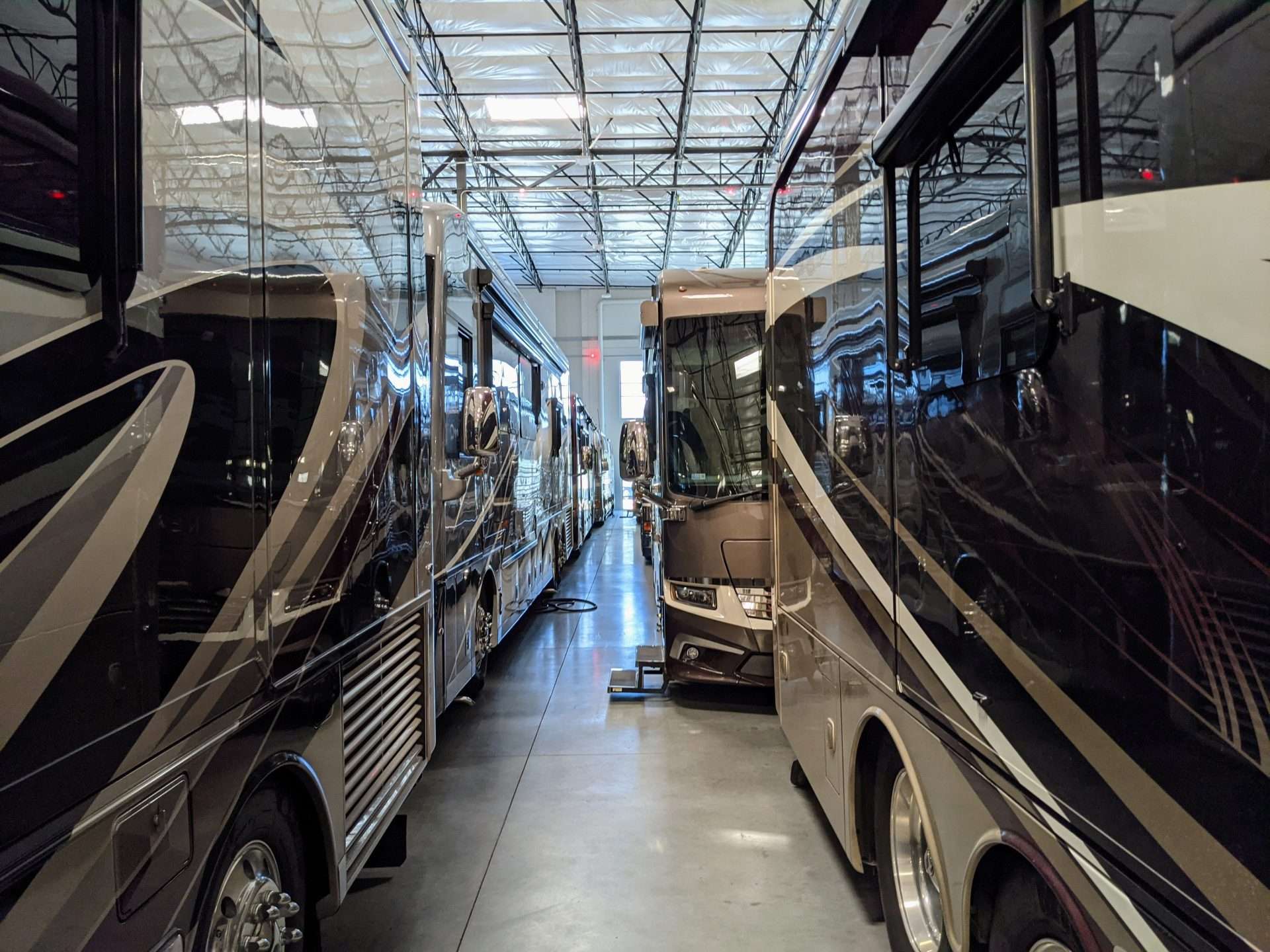 A bunch of Entegra motorhomes parked in warehouse.