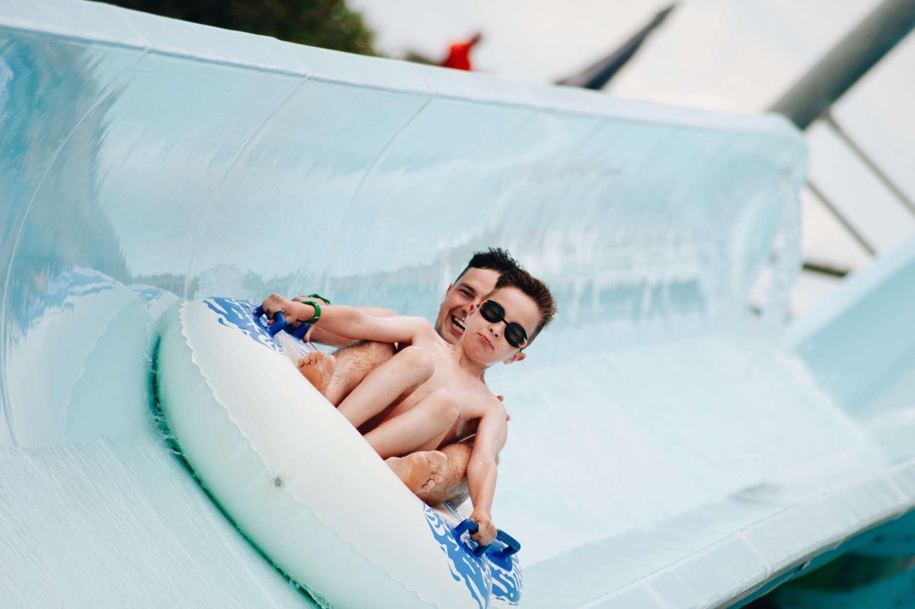 Father and sun sliding down water slide.
