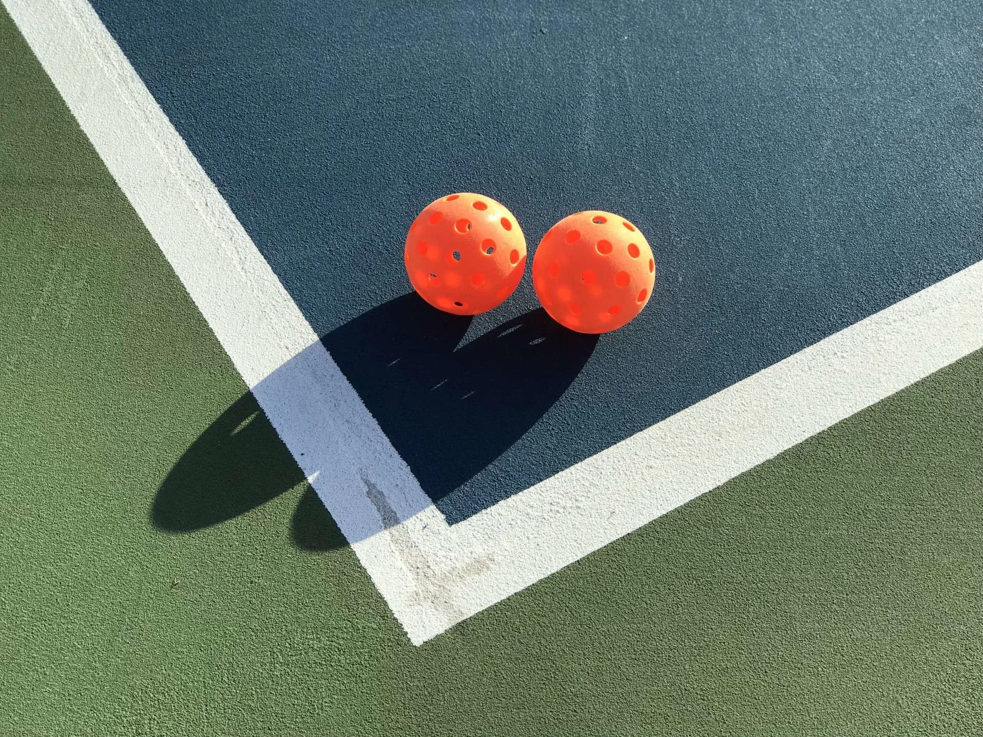 Two pickleball balls on court