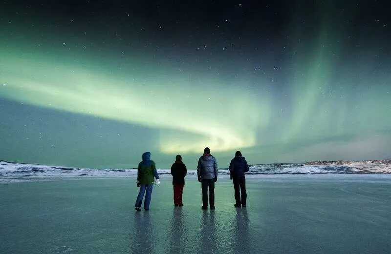 Four friends in front of the Northern Lights.