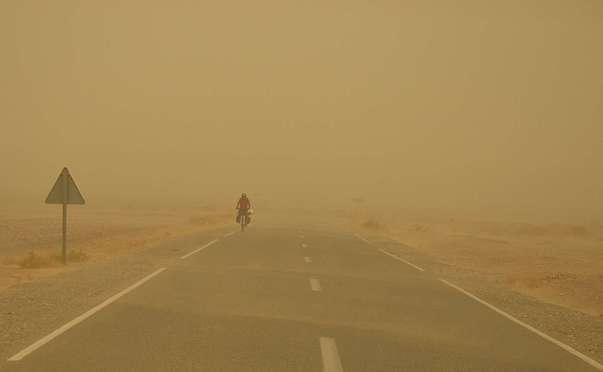 Person bicycling in a sandstorm.