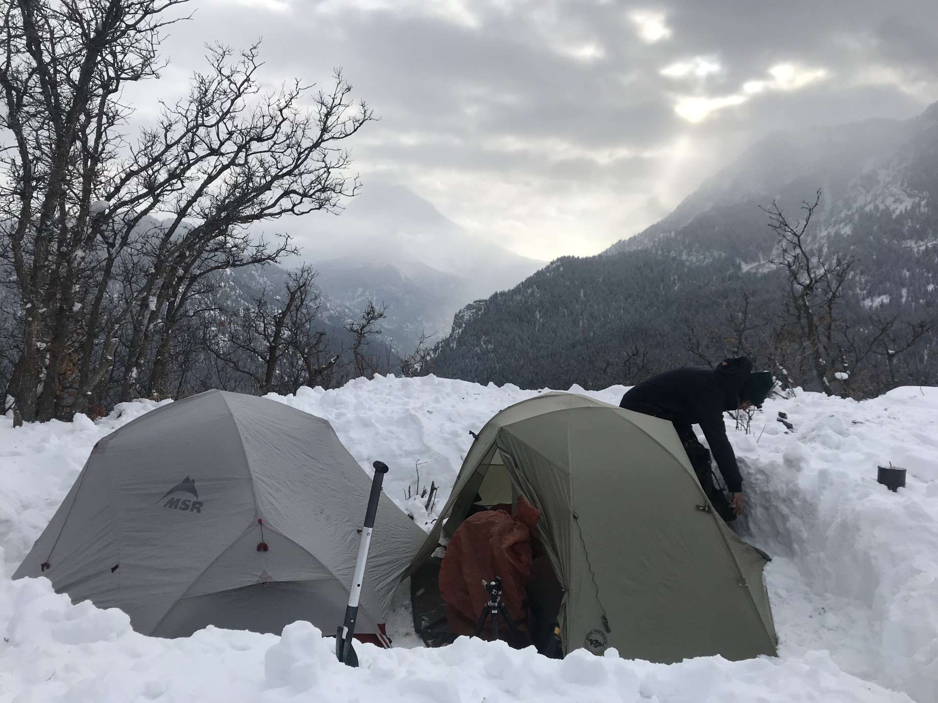 Man using survival shovel to camp in the snow