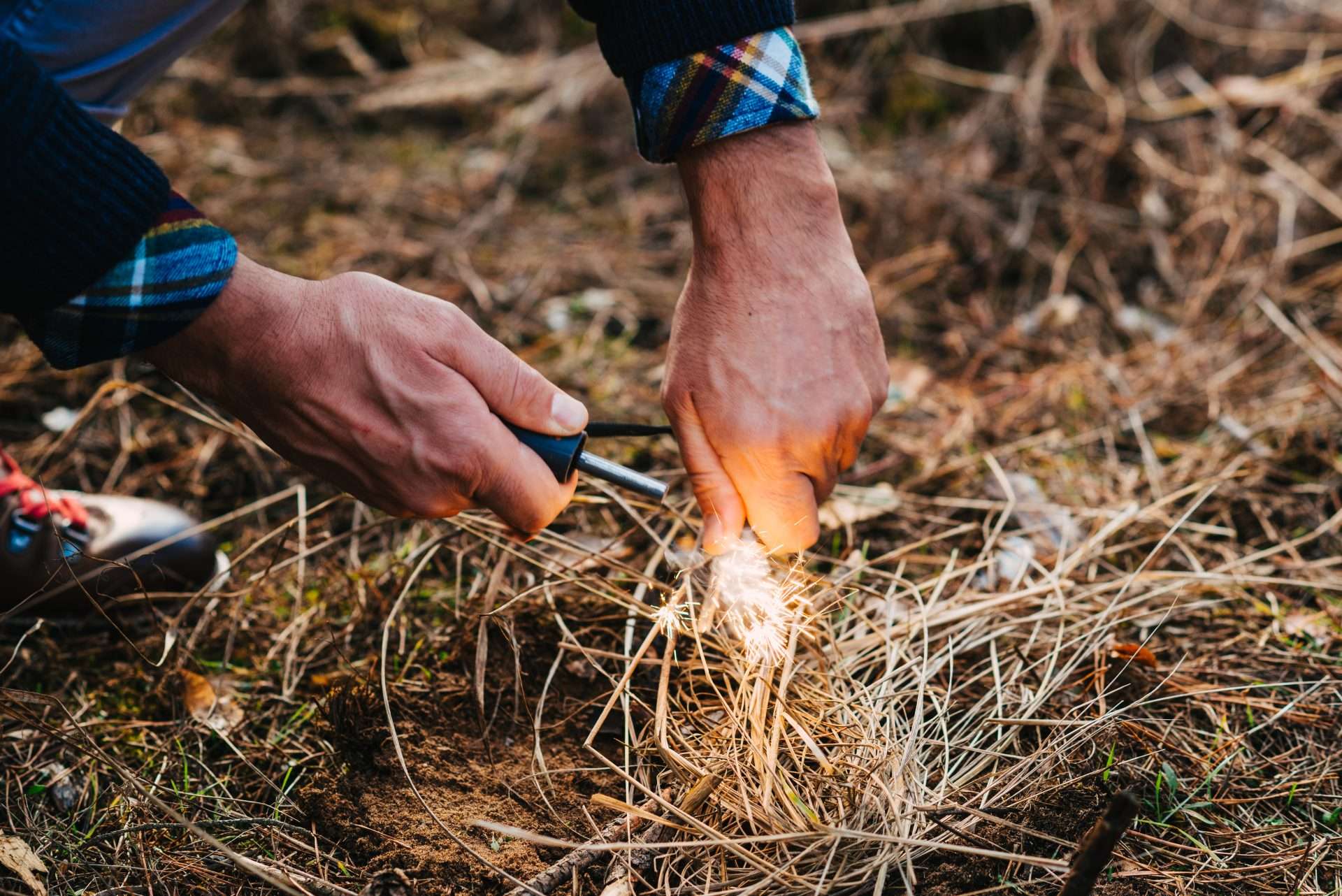 Man using flint and campfire starter to build a campfire