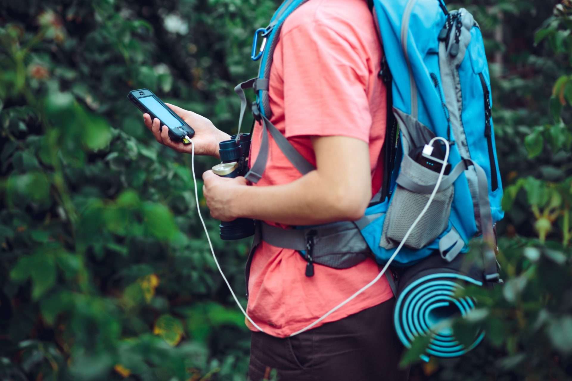 Man using phone in backpack while camping.