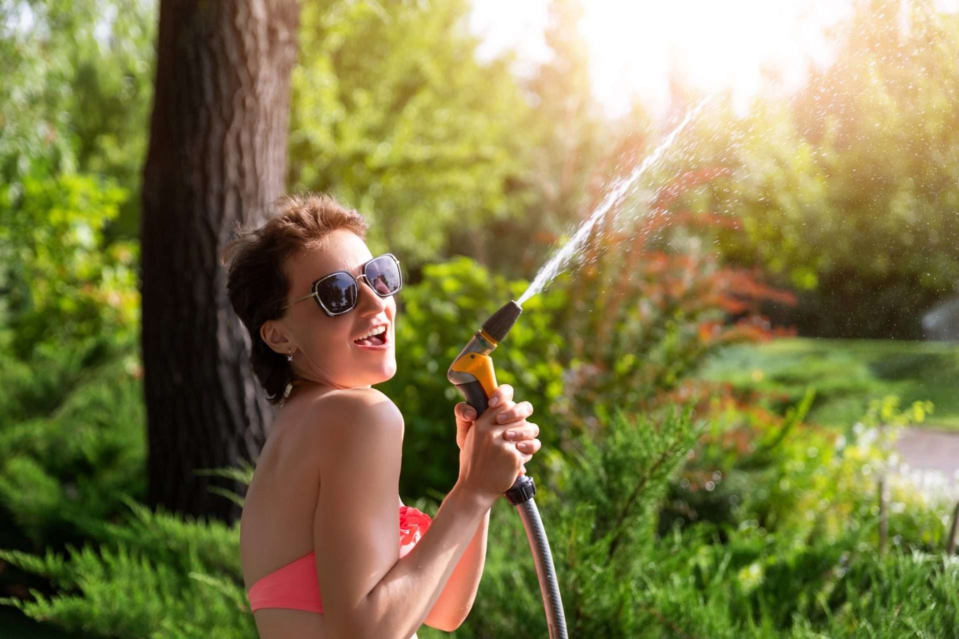 Woman using hose to shower outside
