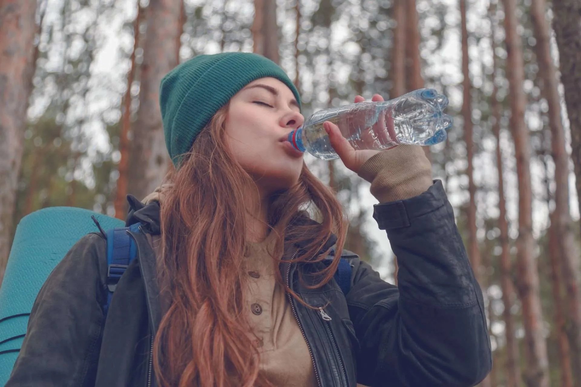 Woman drinking from water bottle while hiking.