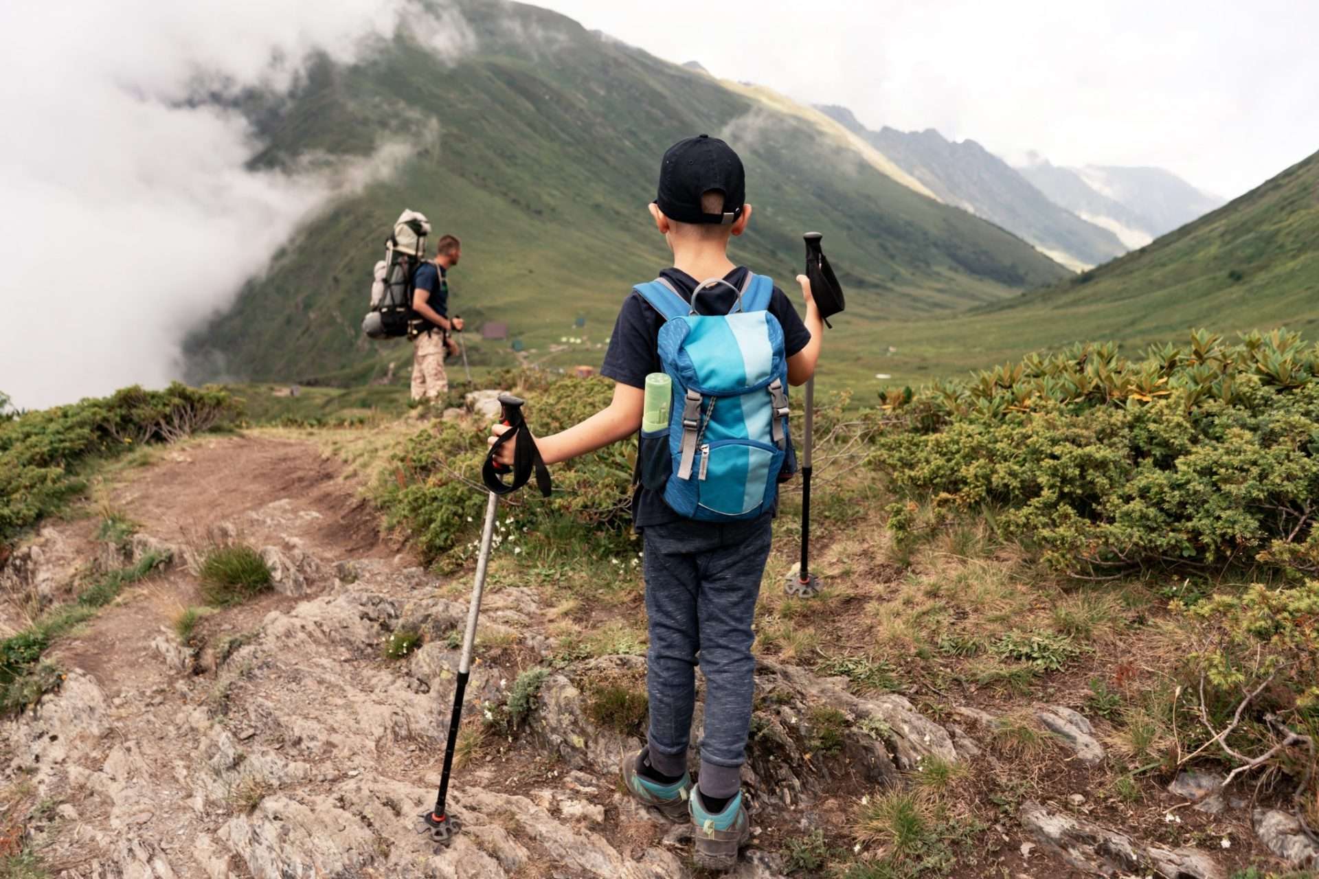 Father and son using hiking poles to hike through a mountain.