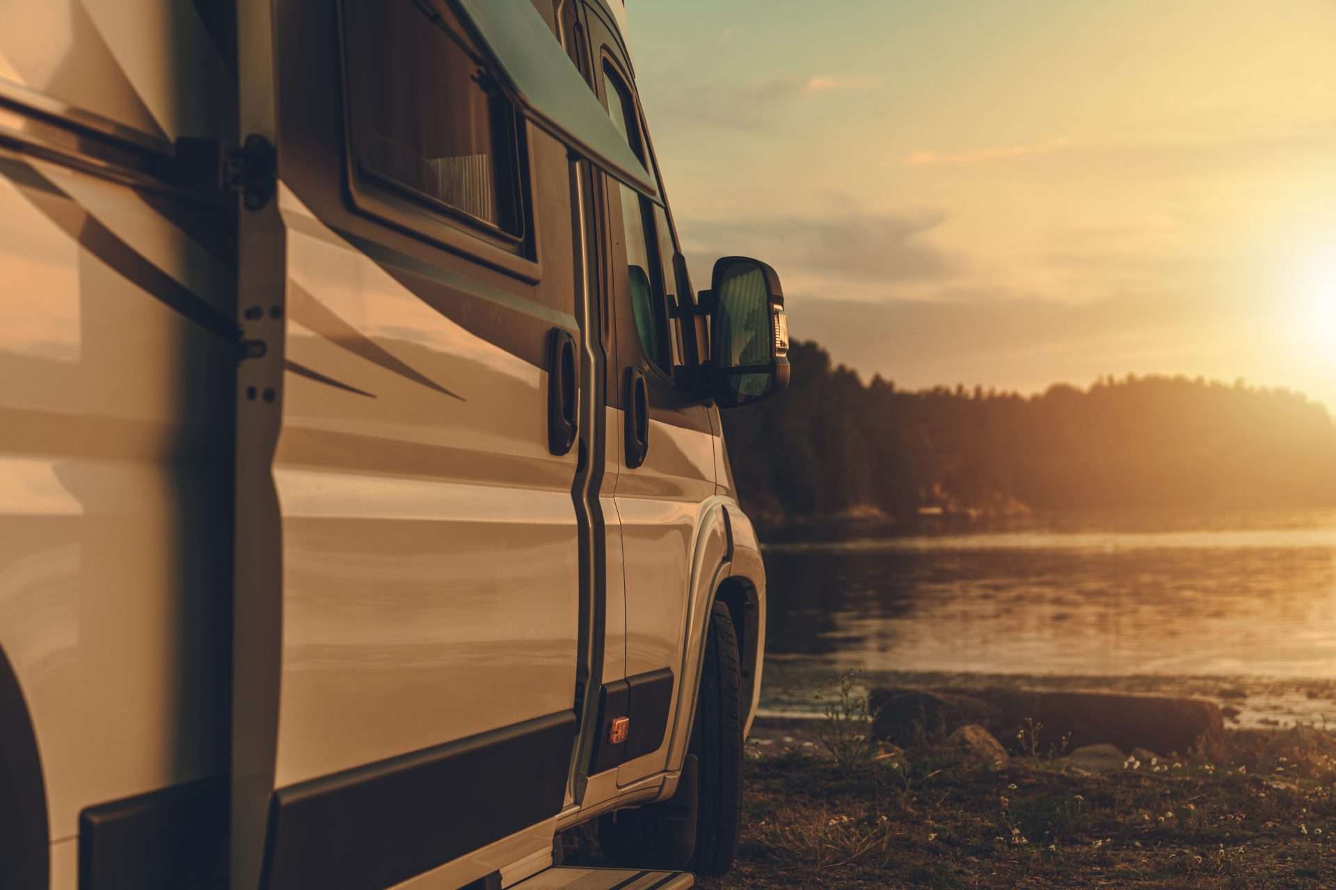 RV parked by lake in sunset