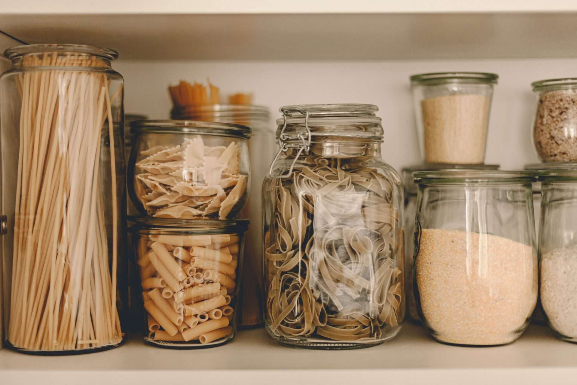 Pasta in glass jars in pantry.