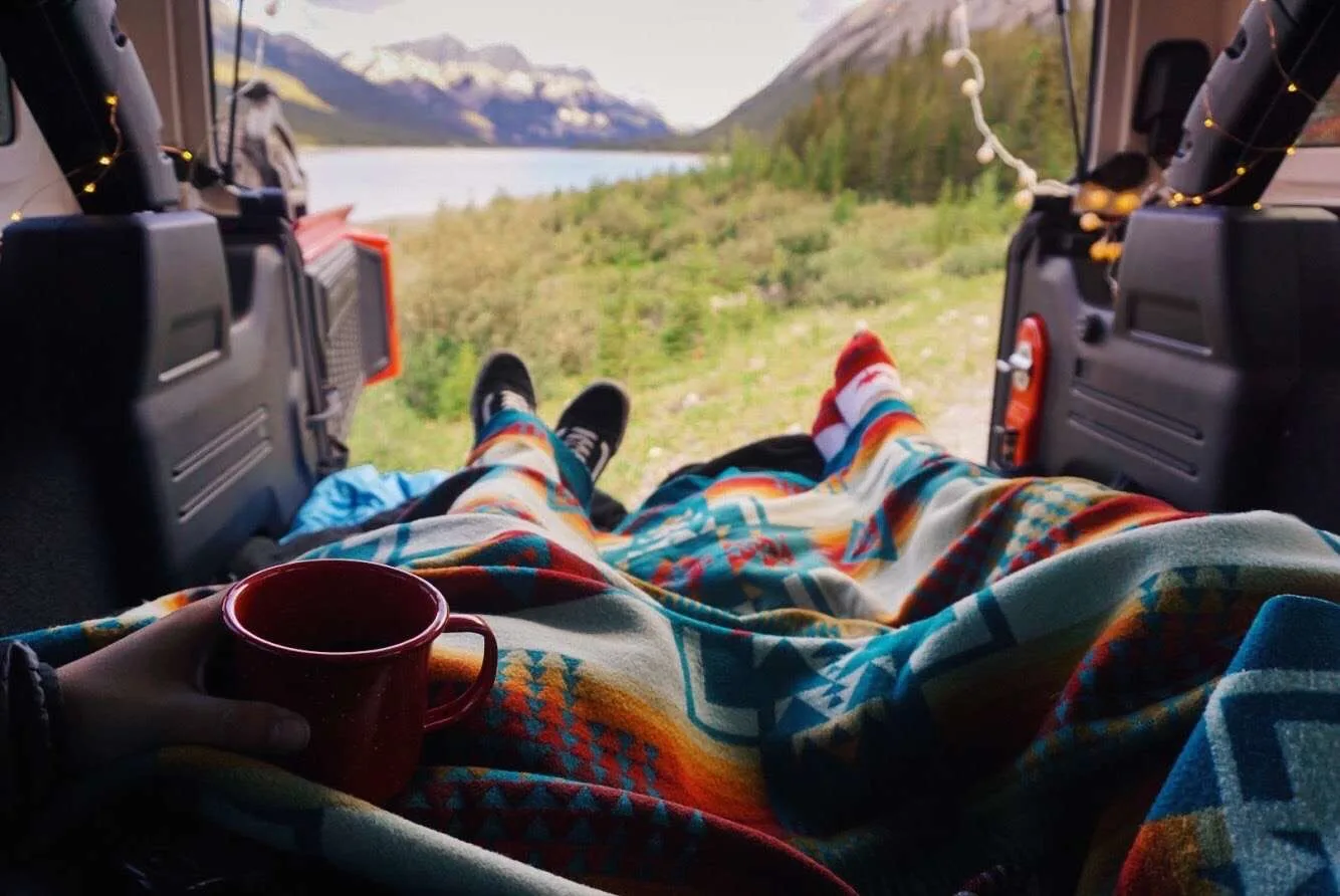 Couple laying together in camper van under blankets.