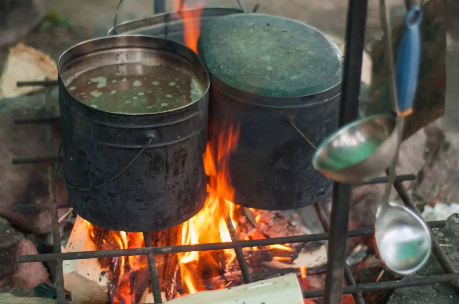 Pots of water being boiled on campfire.